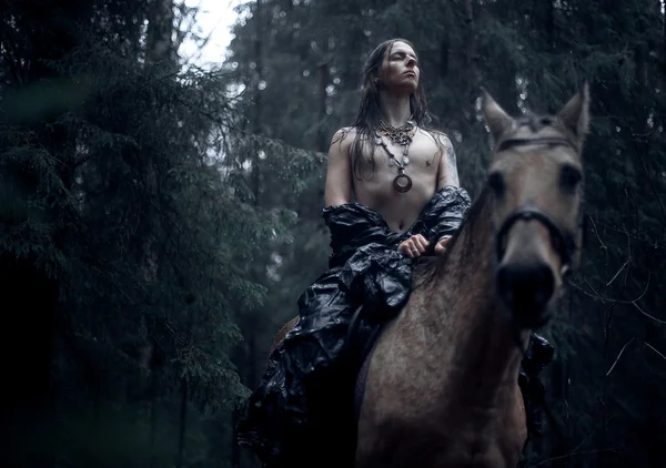 Homme aux cheveux longs avec cheval dans la forêt sombre . — Photo