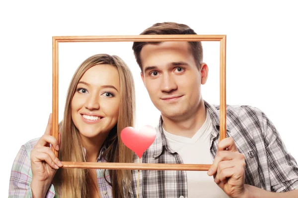 Encantador casal segurando quadro e corações vermelhos — Fotografia de Stock