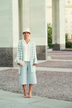 Genç sarışın kadın sokakta yürüyor.