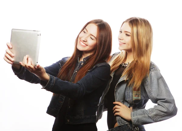 Duas jovens mulheres bonitas tirando um auto-retrato com um tablet — Fotografia de Stock