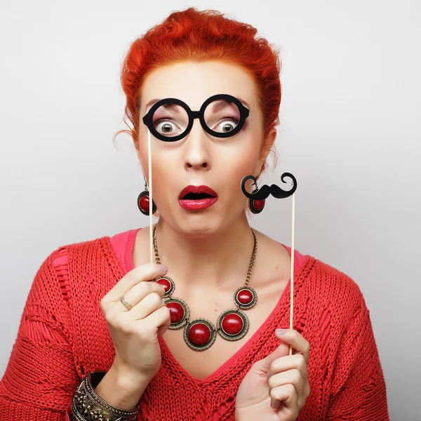 Young woman holding mustache and glasses on a stick. — Stock Photo, Image