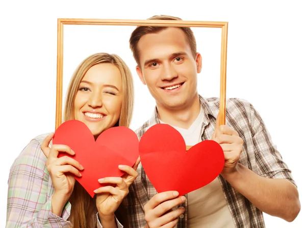 Encantador casal segurando quadro e corações vermelhos — Fotografia de Stock