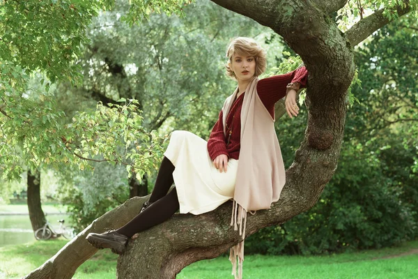 Jonge mooie vrouw die zich voordeed op een boom. — Stockfoto