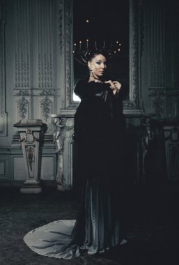 Genç ve güzel bir kadın saray odasında duruyor.