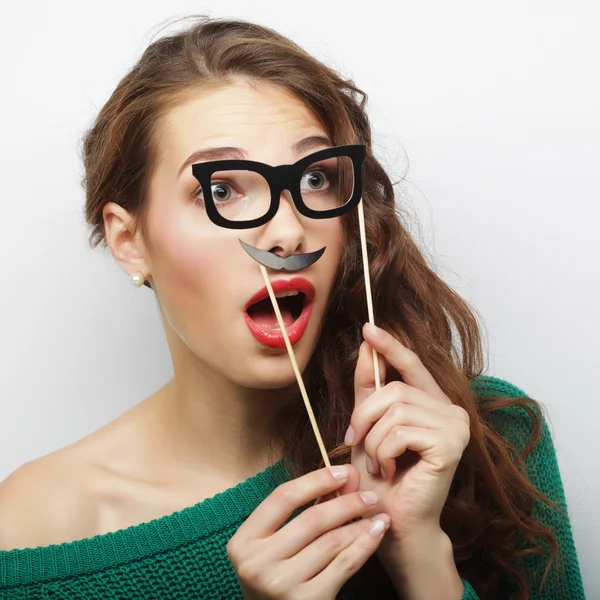 Atractiva joven juguetona sosteniendo bigote y gafas en un — Foto de Stock