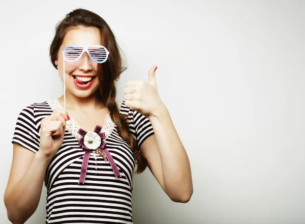 Mujeres jóvenes juguetonas sosteniendo unas gafas de fiesta . — Foto de Stock