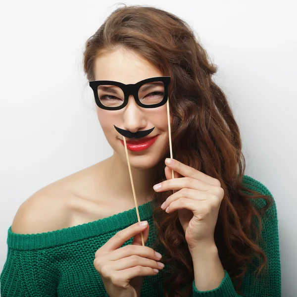 Attractive playful young woman holding mustache and glasses on a — Stock Photo, Image