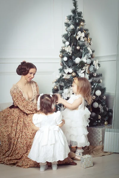 Young mother and her two little daughters near Christmas tree — Stock Photo, Image