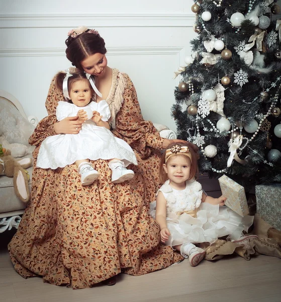年轻的母亲和她近在圣诞树上的两个小女儿 — 图库照片