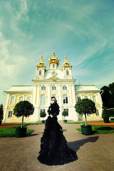 Mulher bonita em vestido preto posando ao lado do palácio . — Fotografia de Stock