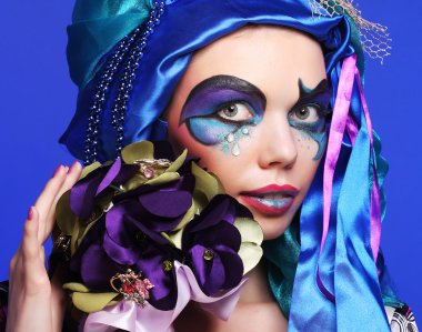 Yaratıcı makyajlı bir kadın bir buket mücevher tutuyor.