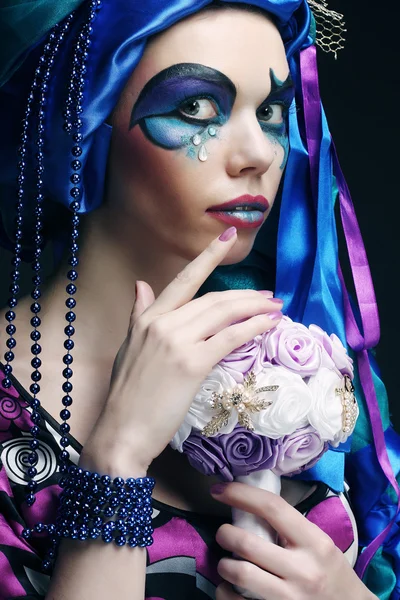Frau mit kreativem Make-up hält einen Strauß Schmuck in der Hand — Stockfoto