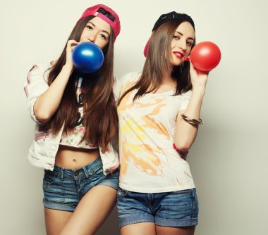 gülümseyen ve renkli balonlar tutan hipster kızlar