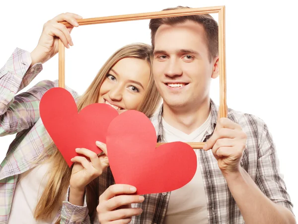 Encantadora pareja sosteniendo marco y corazones rojos —  Fotos de Stock