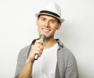 Genç adam mikrofonla şarkı söylüyor.