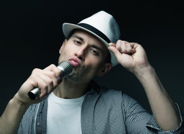 Genç adam mikrofonla şarkı söylüyor.