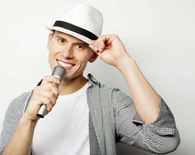 Genç adam mikrofonla şarkı söylüyor.