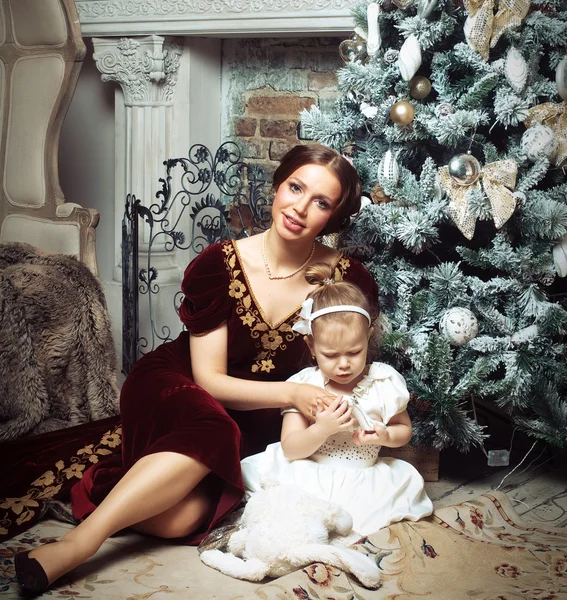 Child with mother receiving near Christmas tree. — Stock Photo, Image