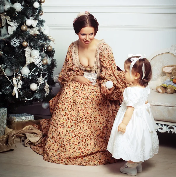 Kind mit Mutter erhält Weihnachtsbaum in der Nähe. — Stockfoto