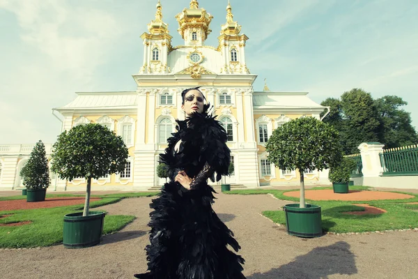 Красивая женщина в черном платье позирует рядом с дворцом . — стоковое фото