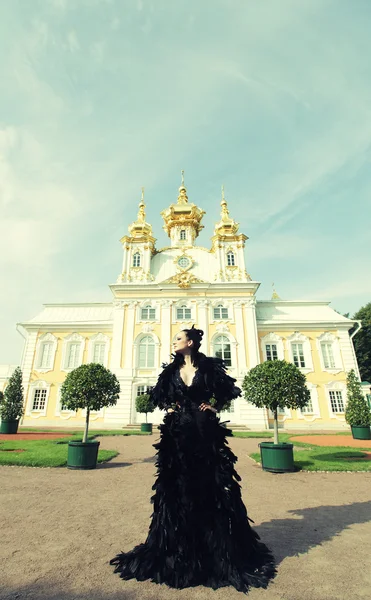 Fekete ruhában pózol a palota mellett a gyönyörű nő. — Stock Fotó