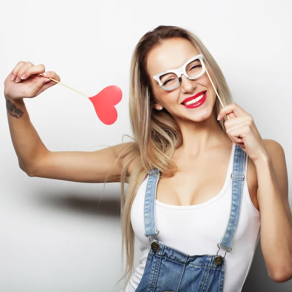 Playful young woman holding a party heart. — Stock Photo, Image