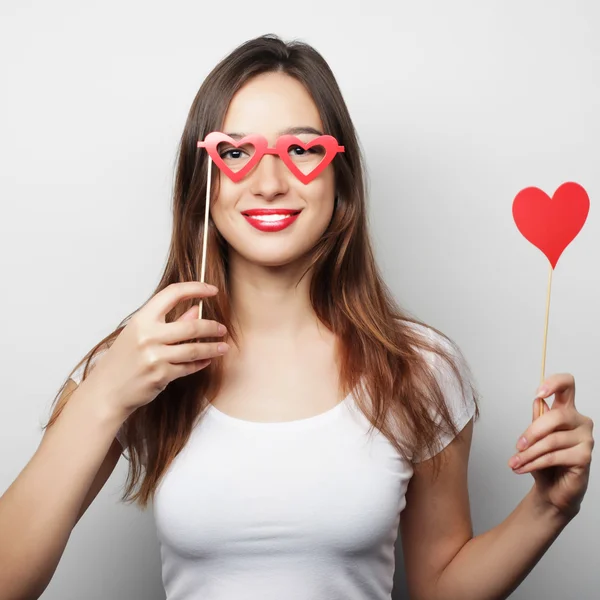 Jovencita juguetona sosteniendo un corazón de fiesta . — Foto de Stock