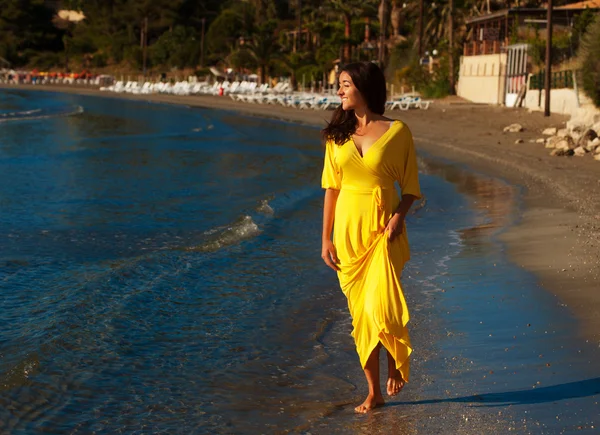 Mulher com vestido amarelo em uma praia . — Fotografia de Stock