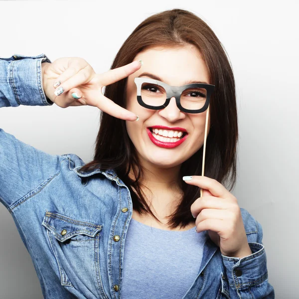 Imagen de fiesta. Jovencita juguetona sosteniendo unas gafas de fiesta . — Foto de Stock