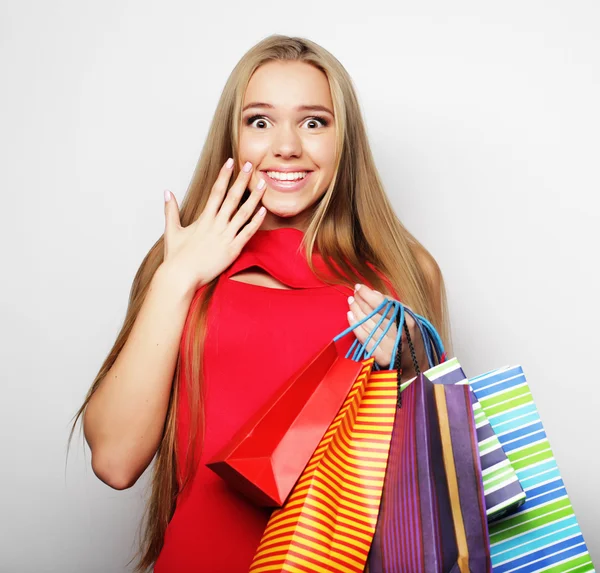 Junge Frau trägt rotes Kleid mit Einkaufstaschen. — Stockfoto