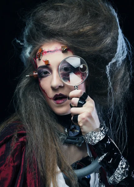 Женщина с творческим макияжем держа увеличительное стекло — стоковое фото