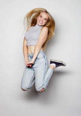 Gülümseyen genç kadın havada zıplıyor.