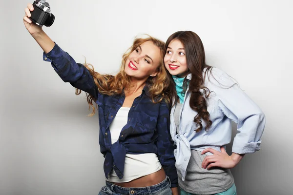 Glückliche Freundinnen beim Fotografieren, vor grauem Hintergrund — Stockfoto