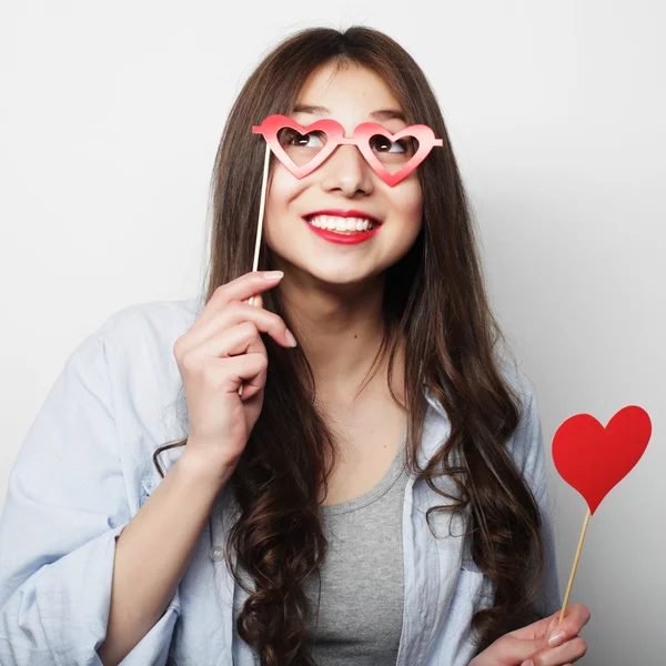 Jovencita juguetona sosteniendo un corazón de fiesta . — Foto de Stock