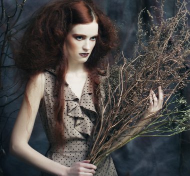 Kuru dallarla süslenmiş parlak bir kadın.