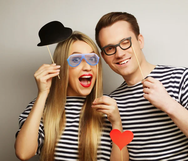 Couple holding party glasses and hat on sticks — Stock Photo, Image