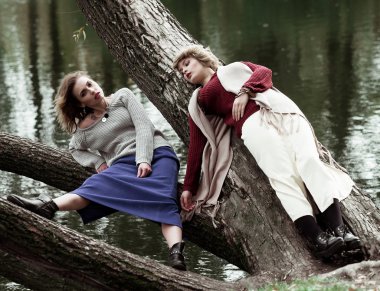 iki genç güzel kadın bir ağaç üzerinde poz.