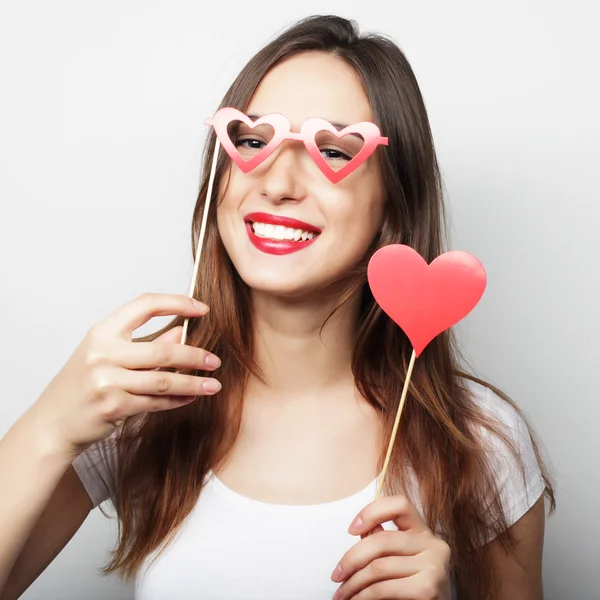 Jovencita juguetona sosteniendo un corazón de fiesta . — Foto de Stock