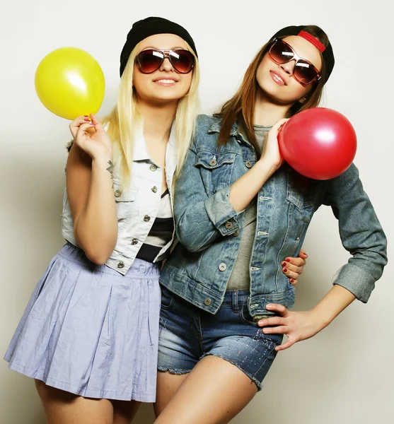 Hipsterjenter smiler og holder fargede ballonger – stockfoto