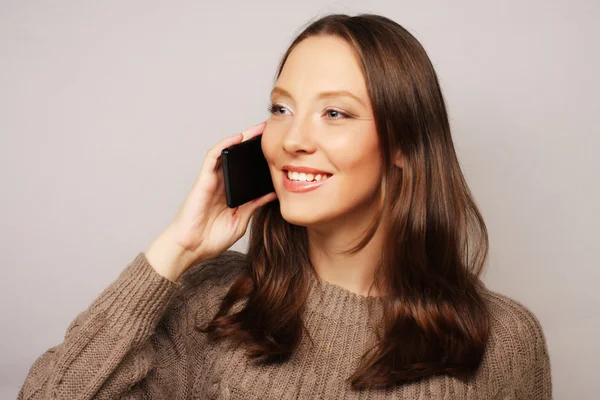 Kvinna med en mobiltelefon isolerad på en vit bakgrund Stockbild