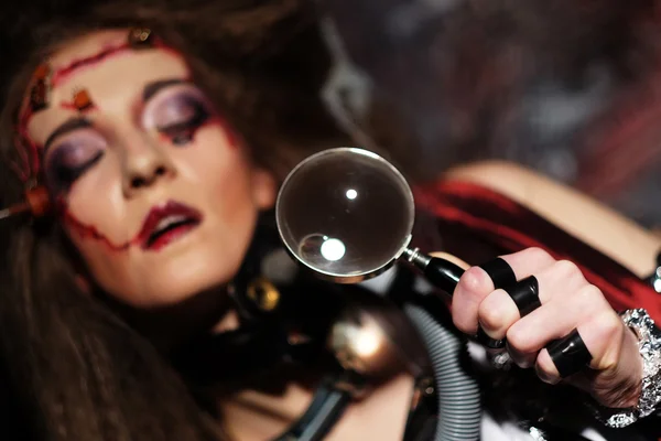 Woman with creative make up holding a magnifying glass — Stock Photo, Image