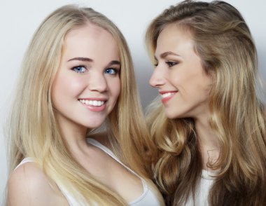 İki genç kız arkadaş birlikte durup eğleniyorlar..