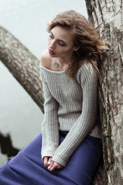 Bir ağaç üzerinde poz genç güzel kadın.