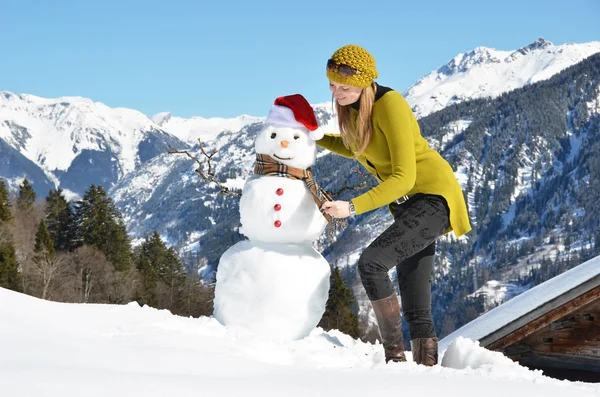 Meisje versieren een sneeuwpop — Stockfoto