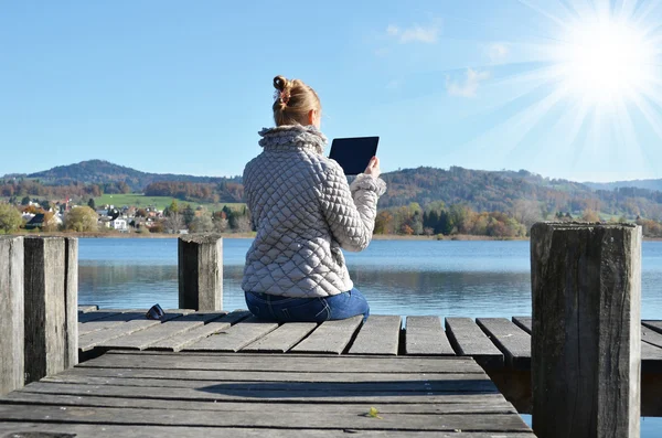 Girl reading tablet against lake. — Stock Photo, Image