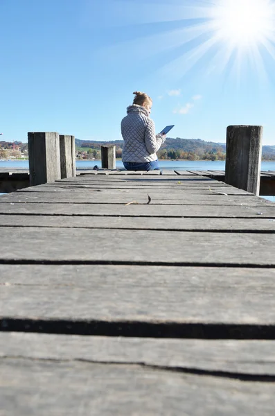Girl reading tablet against lake. — Stock Photo, Image