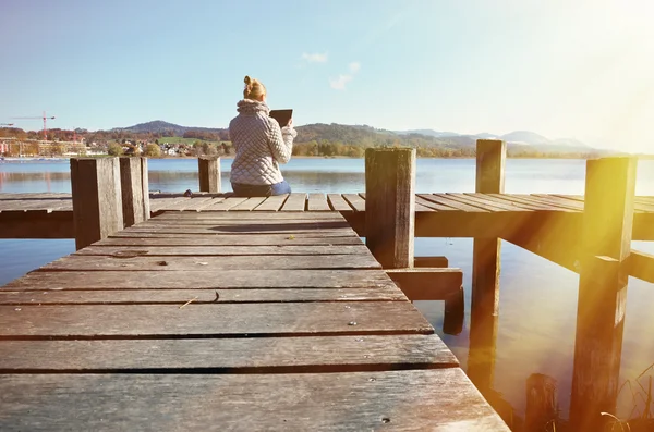 Girl reading tablet against lake. — Stock Photo, Image