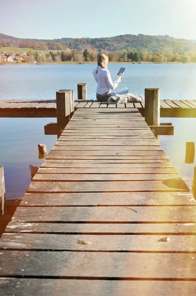 Mädchen liest Tablet gegen See. — Stockfoto