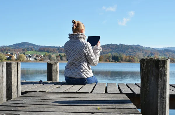 Dívka čtení tablet proti jezero. — Stock fotografie