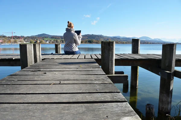 Dívka čtení tablet proti jezero. — Stock fotografie